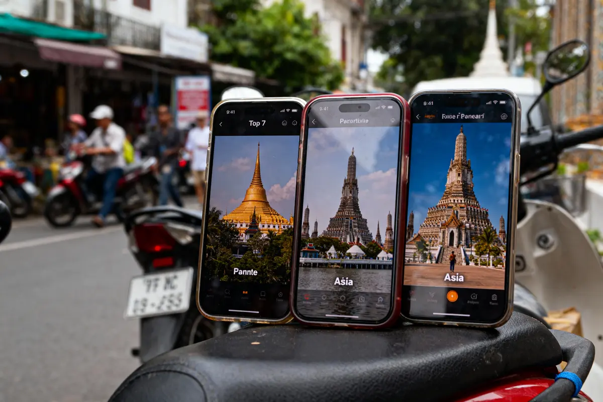 Trois smartphones affichant des images de pagodes asiatiques, posés sur un scooter dans une rue animée.