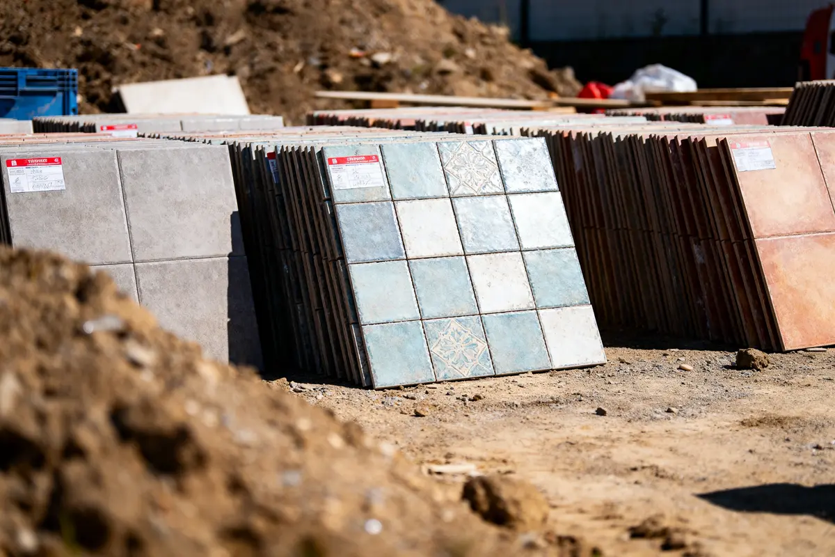 Carreaux de céramique empilés sur un chantier en extérieur, terre en premier plan.