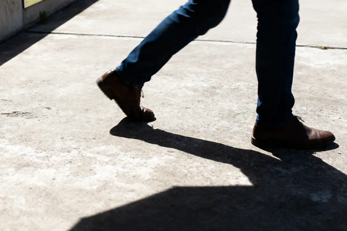 Personne marchant sur une dalle en beton avec ombre visible au sol