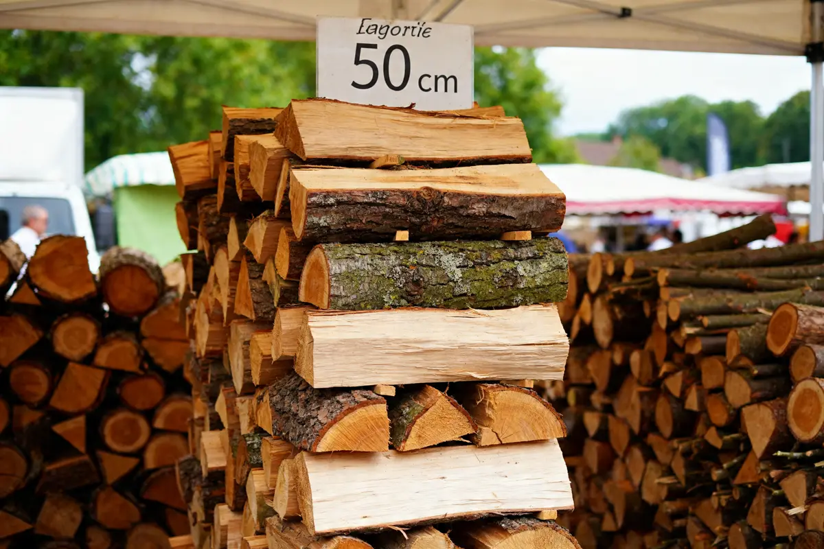 Bûches empilées sous abri avec indication prix du stère de bois en 50 cm