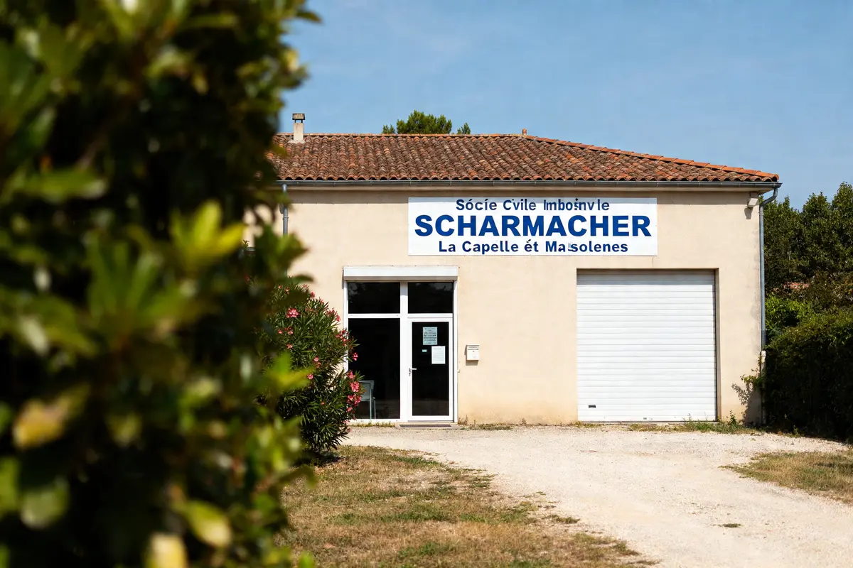 Bâtiment avec enseigne Scharcher entouré de verdure et ciel bleu en arrière-plan